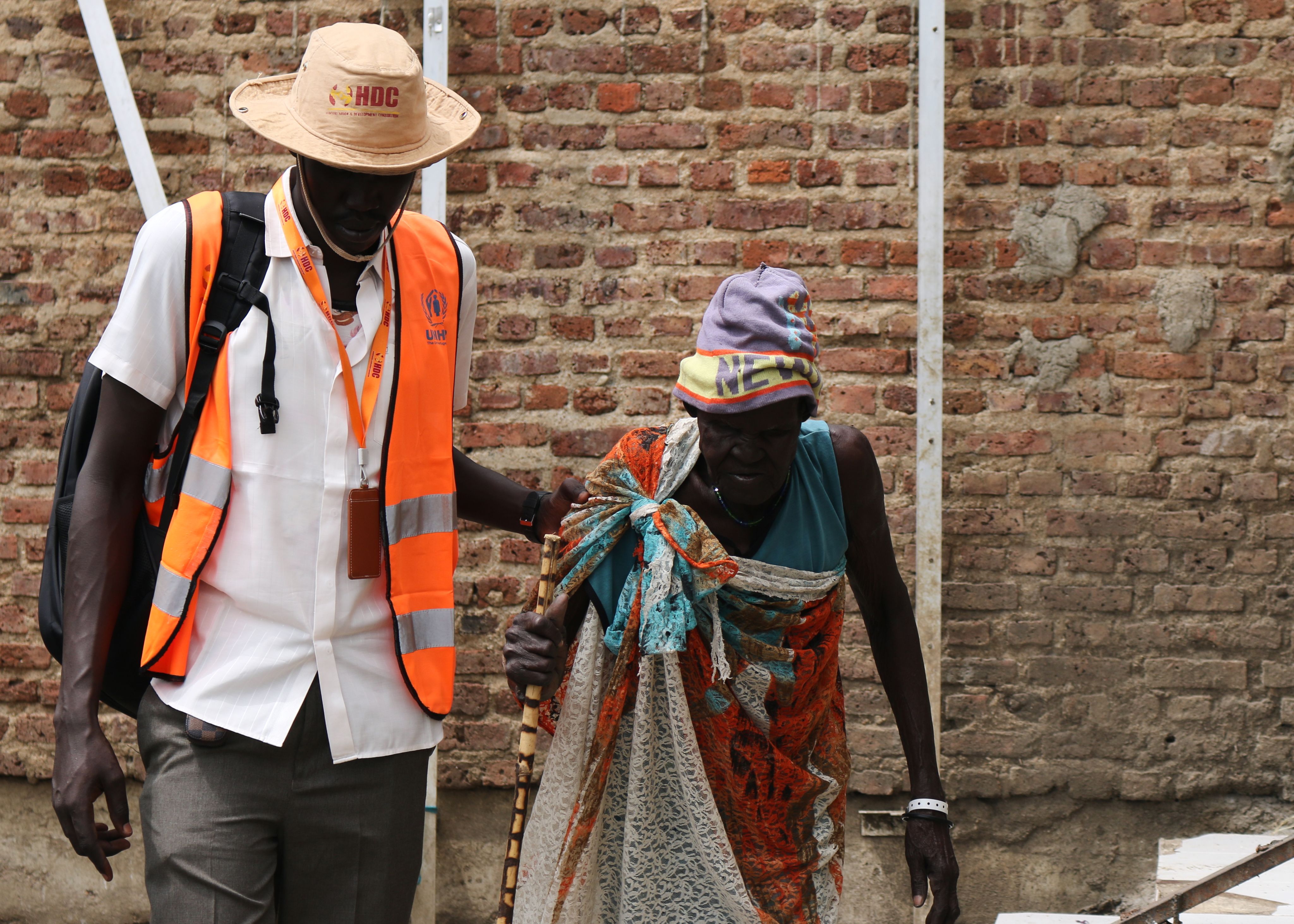 HDC staff member helping Nyawech Deng Duop, an older lady in South Sudan, with walking.