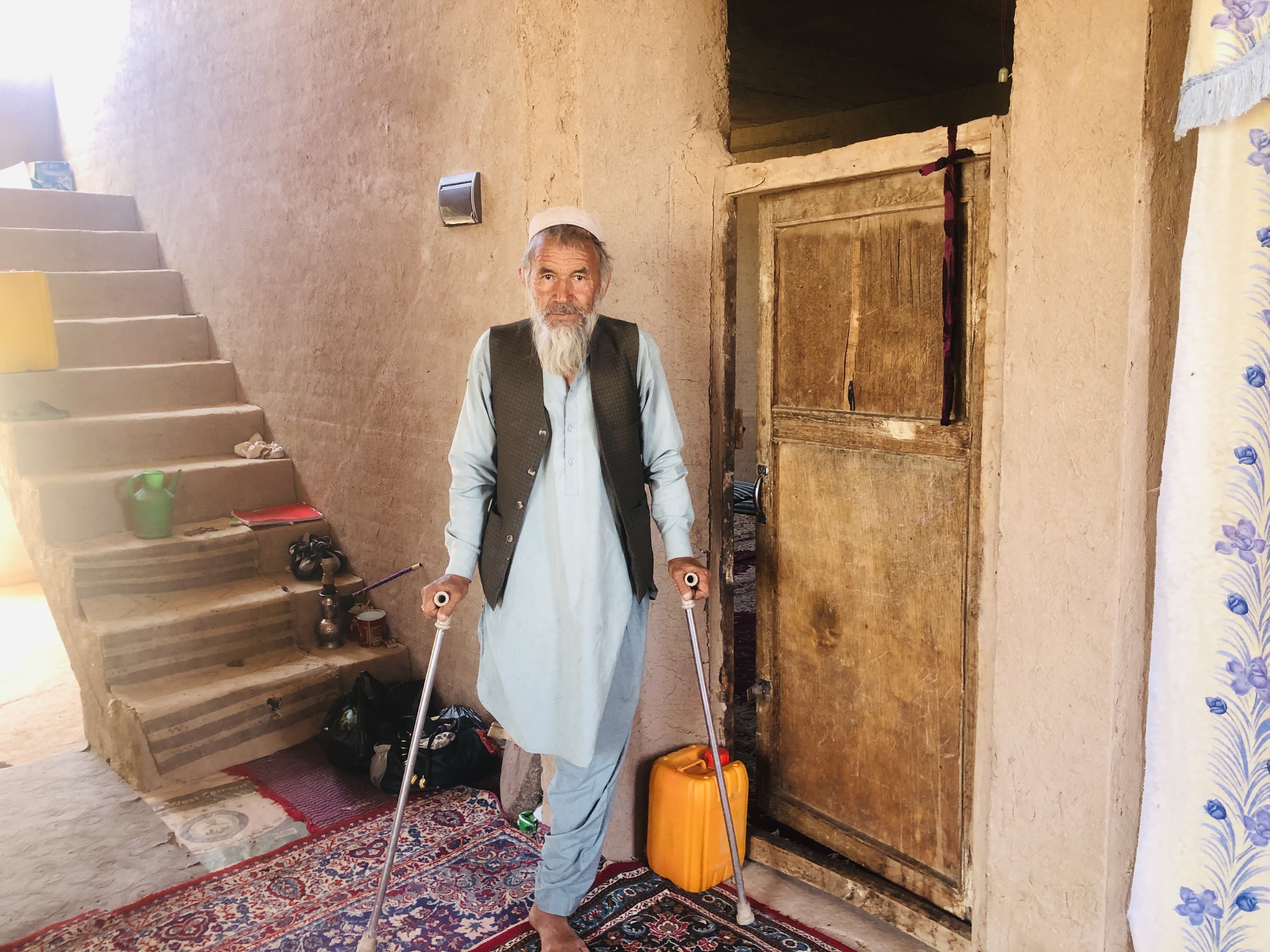 Older man in Afghanistan stands with crutches.