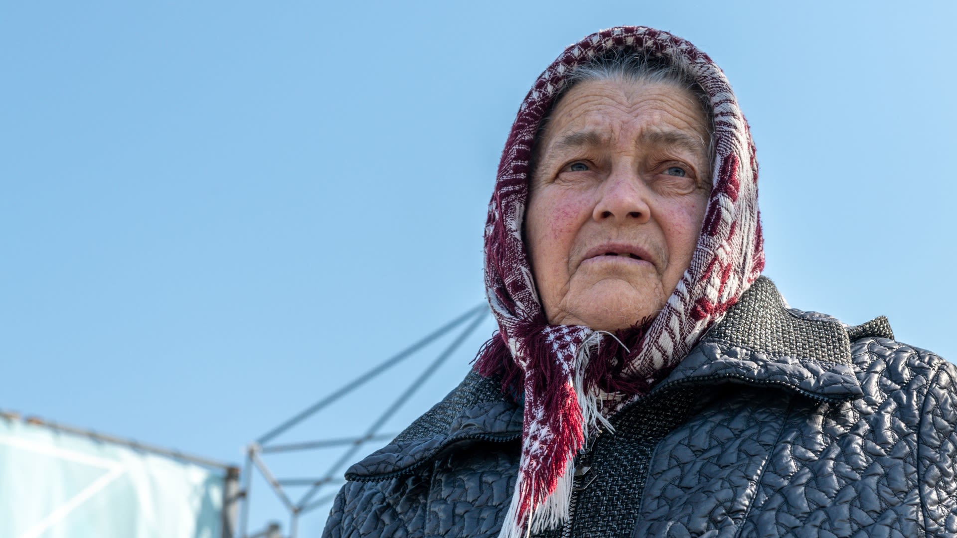 Older Ukranian woman dressed warmly in a thick headscarf with a worried expression