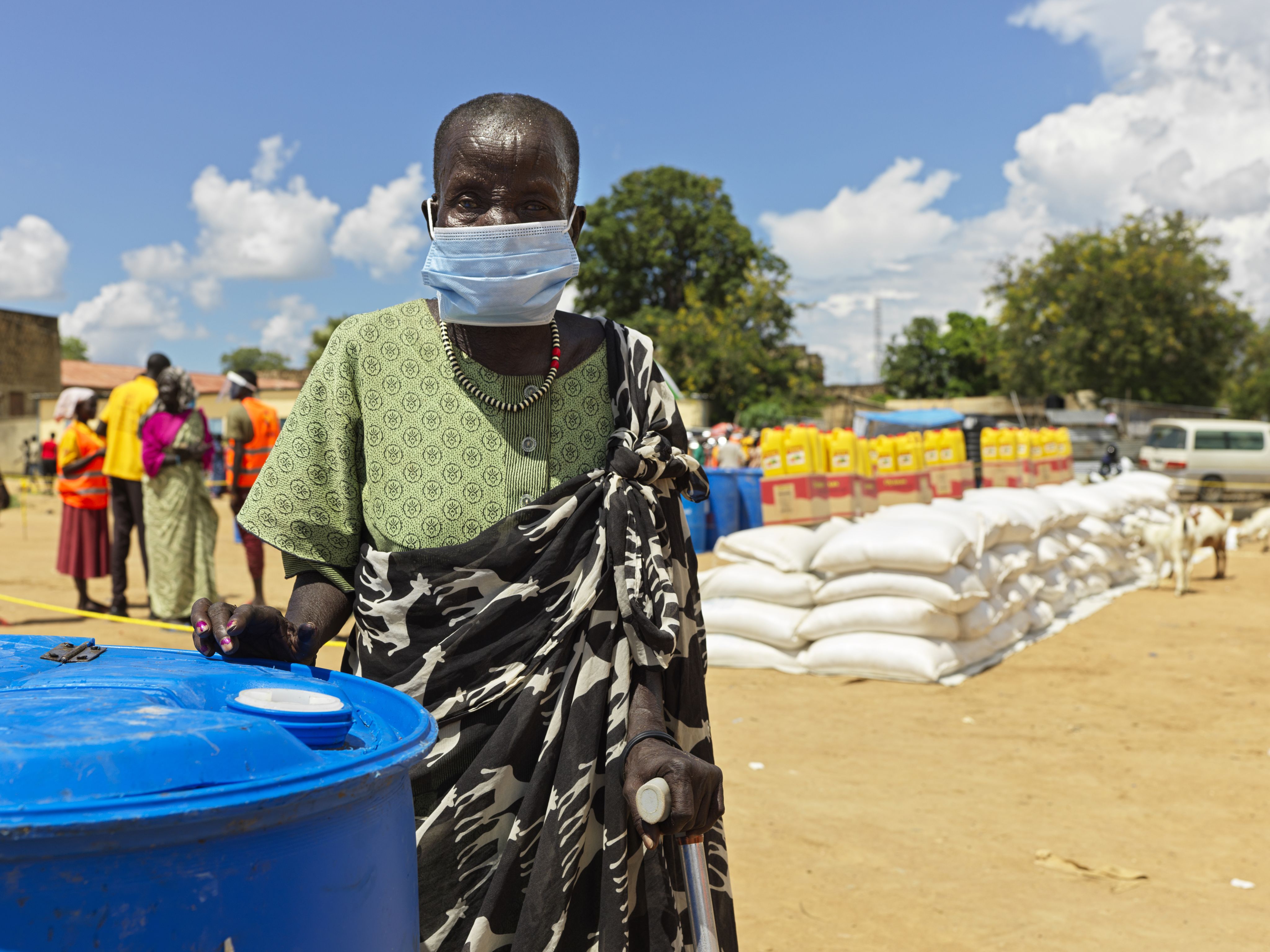 Older woman in face mask stands in front of an aid distribution